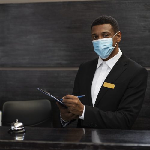 receptionniste masculin en costume au travail portant un masque medical min